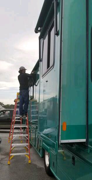 RV Awnings' worker replaces an awning fabric next to an aqua RV. Text below the picture says 
