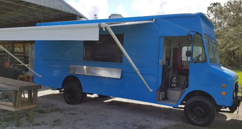 A blue food truck with an extended custom awning