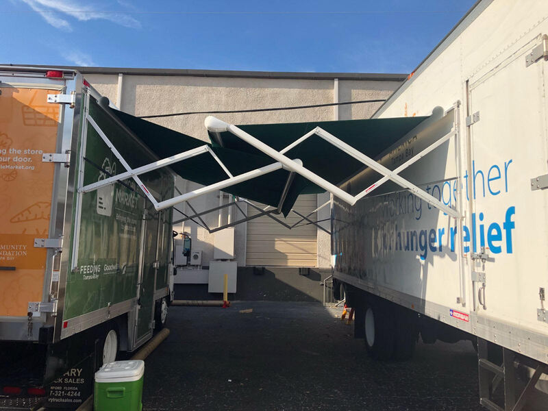 A food truck and a semi truck trailer with two extended custom awnings