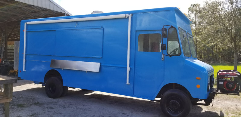 A blue food truck with a custom awning