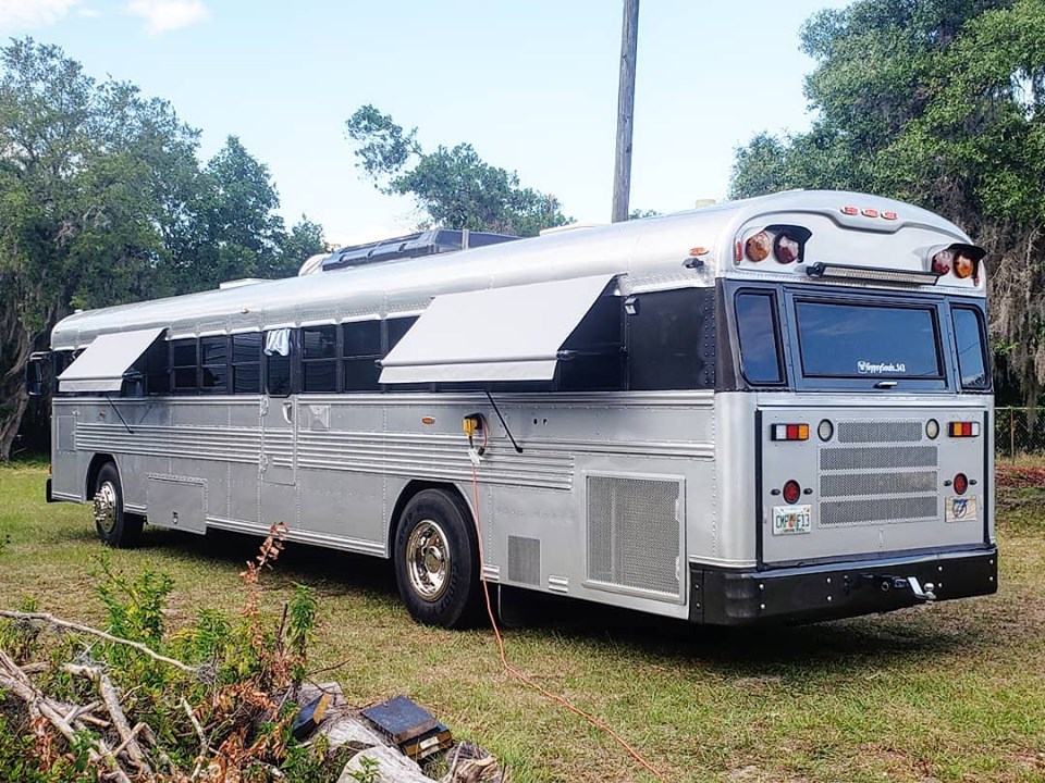 A silver bus with a custom awning