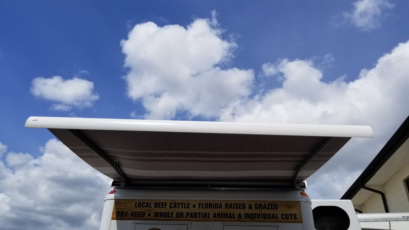 Blue sky and a refrigerated meat truck with an extended custom awning 