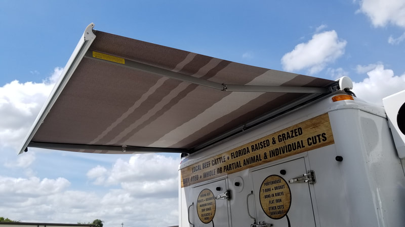 Blue sky and a refrigerated meat truck with an extended custom awning 