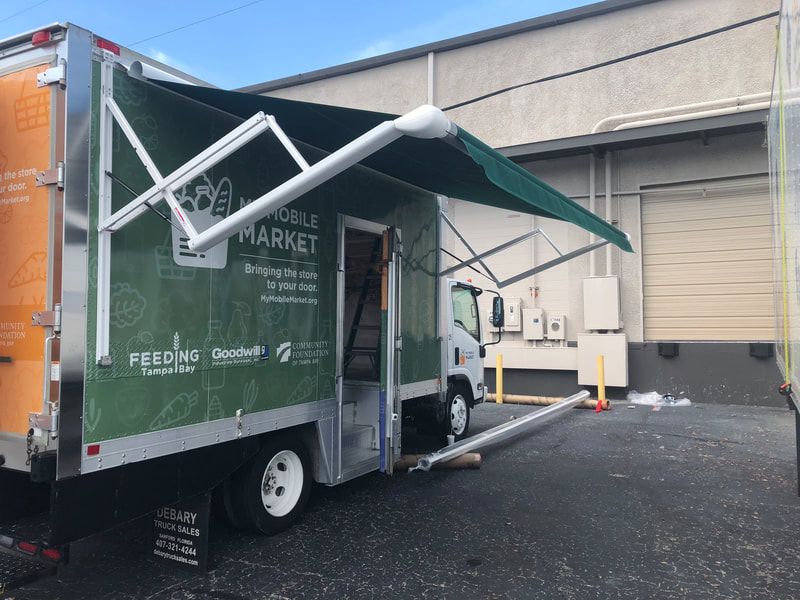 A warehouse parking lot with a food truck and extended custom awning