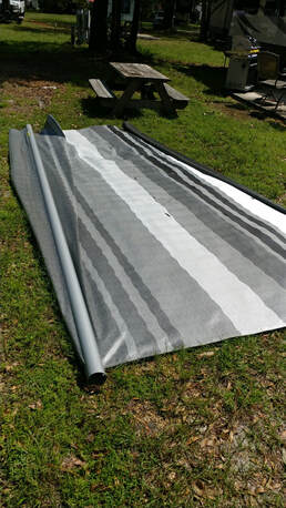 A grey awning lying on the ground 