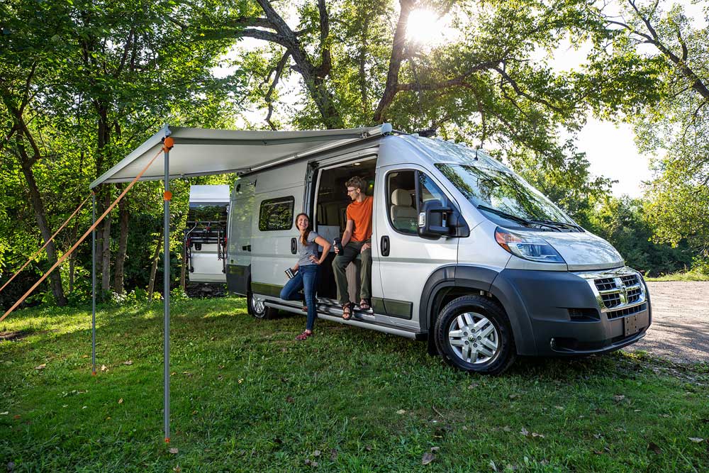 A couple relaxing underneath a van with an HD awning stabilizer